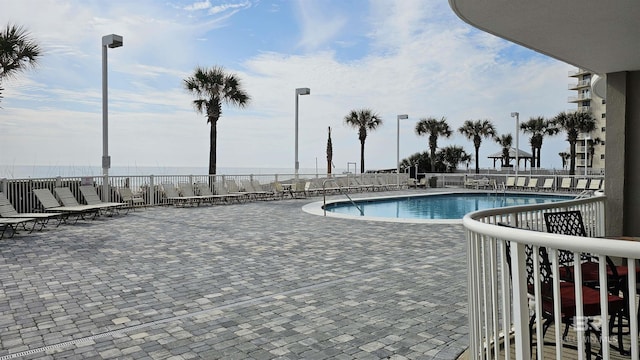 pool with a patio area and fence