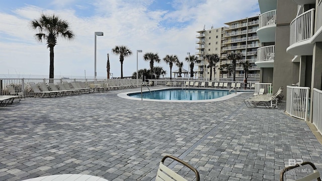 community pool with fence and a patio area