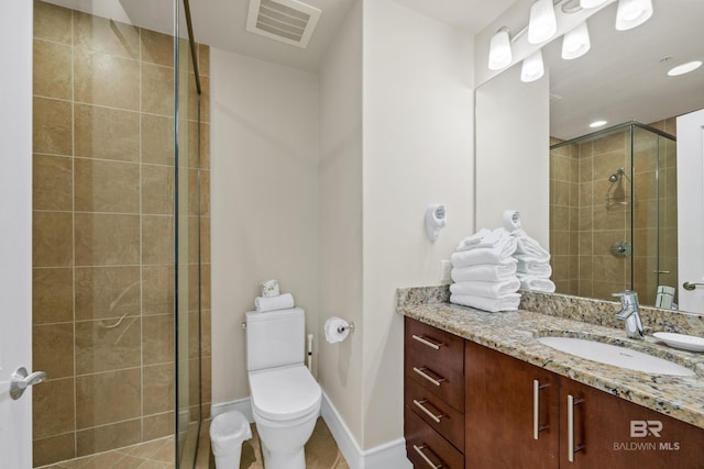 bathroom featuring tile patterned flooring, a shower with door, vanity, and toilet