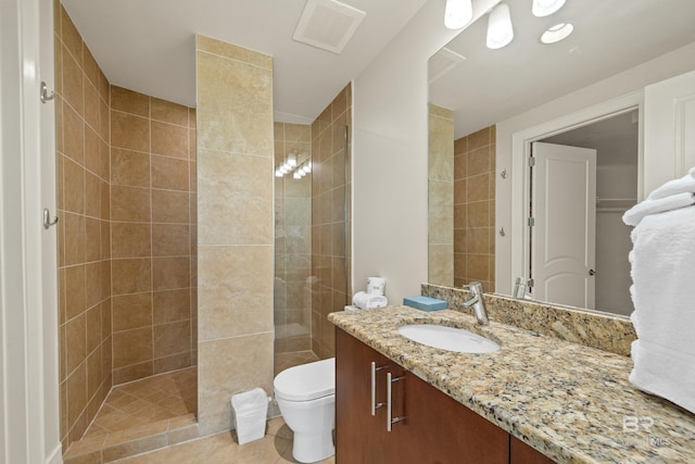 bathroom with tiled shower, vanity, toilet, and tile patterned flooring