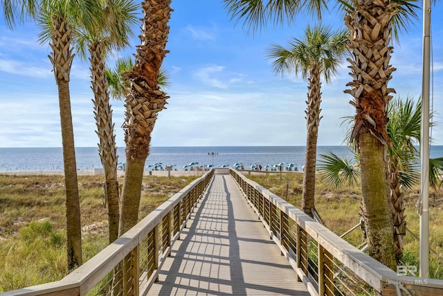 view of dock with a water view and a beach view