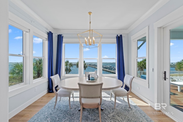 4029 Landfall Dr, Pensacola, FL 32507 - dining space featuring baseboards, light wood-type flooring, a water view, and an inviting chandelier