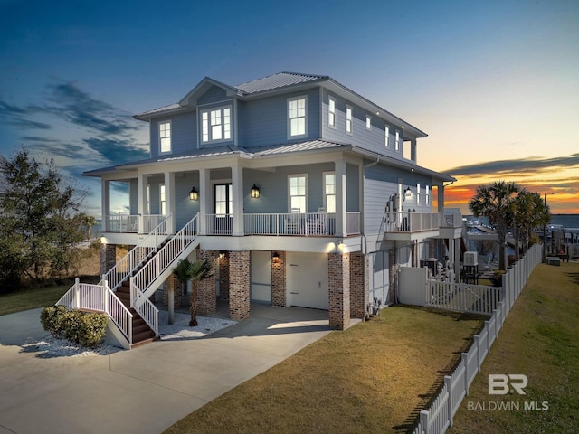 4029 Landfall Dr, Pensacola, FL 32507 - beach home with metal roof, an attached garage, concrete driveway, brick siding, and a porch