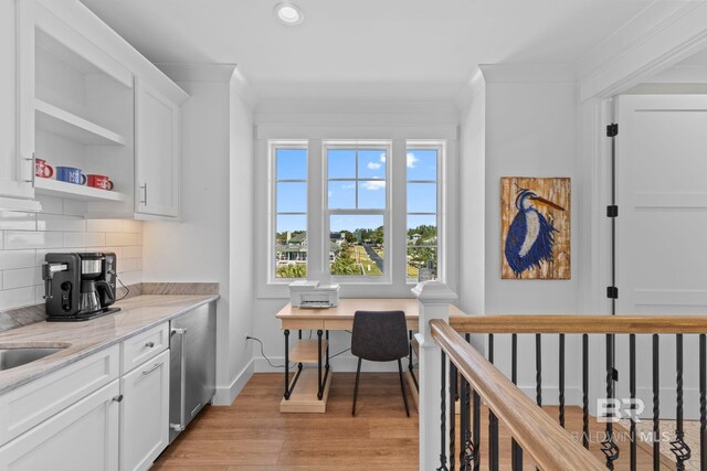 4029 Landfall Dr, Pensacola, FL 32507 - kitchen with crown molding, white cabinets, light wood-style flooring, and backsplash