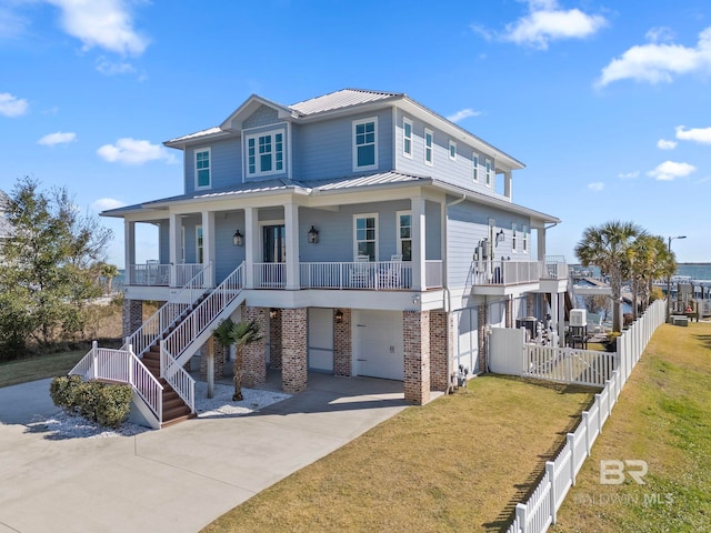 4029 Landfall Dr, Pensacola, FL 32507 - beach home with metal roof, brick siding, a front lawn, driveway, and covered porch
