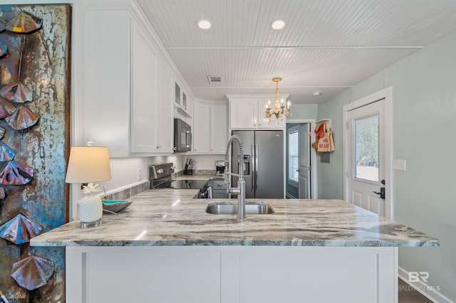 kitchen featuring white cabinetry, a peninsula, light stone countertops, and stainless steel appliances