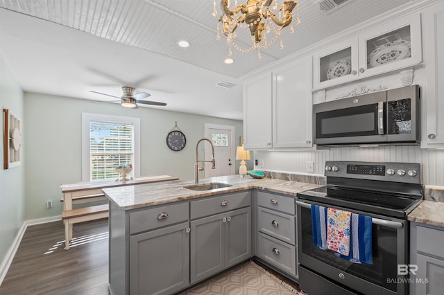 kitchen with a sink, stainless steel appliances, a peninsula, and gray cabinets