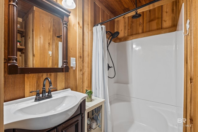 full bathroom with vanity, a shower with shower curtain, and wood walls