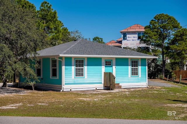 view of front of property with a front yard, fence, and roof with shingles