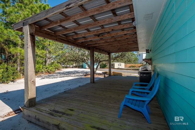 wooden terrace featuring an outbuilding, area for grilling, and a storage shed