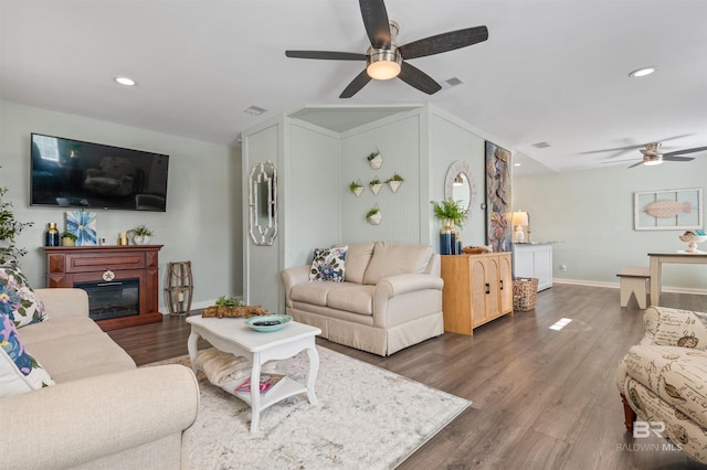 living area with baseboards, wood finished floors, visible vents, and ceiling fan