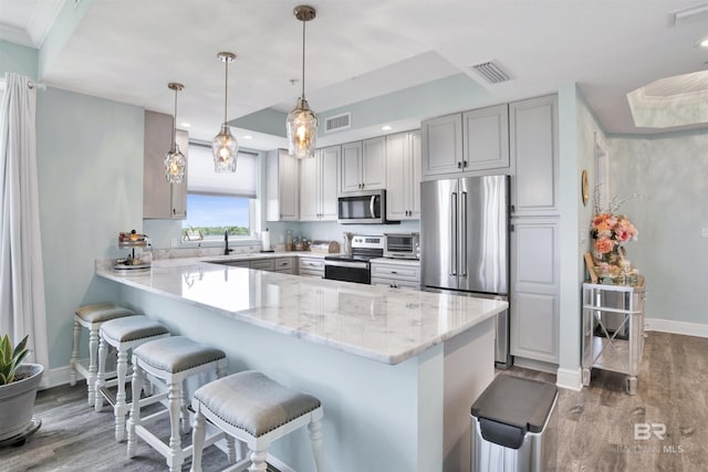 608 Lost Key Dr Unit 705C, Pensacola, FL 32507 - kitchen featuring appliances with stainless steel finishes, a peninsula, baseboards, wood finished floors, and a kitchen bar