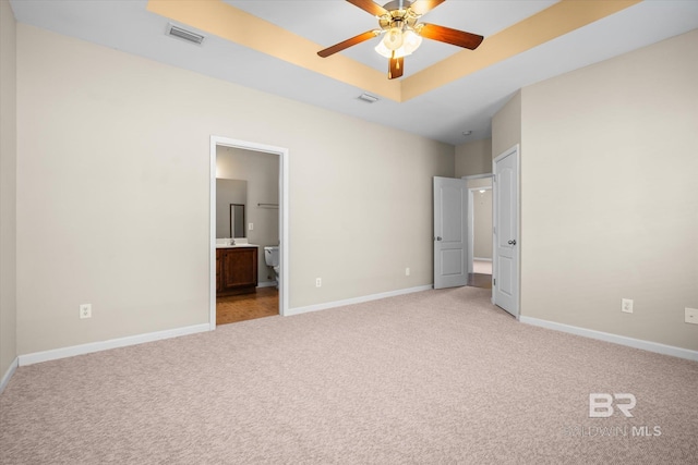 unfurnished bedroom featuring light carpet, ensuite bathroom, and ceiling fan