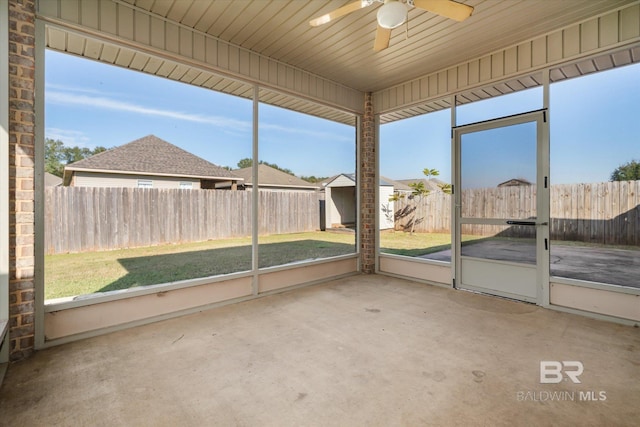 unfurnished sunroom with ceiling fan, a healthy amount of sunlight, and wood ceiling