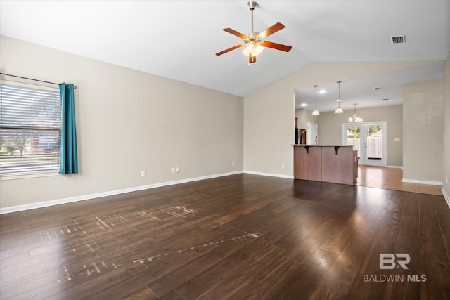 unfurnished living room featuring ceiling fan with notable chandelier, dark hardwood / wood-style flooring, lofted ceiling, and french doors