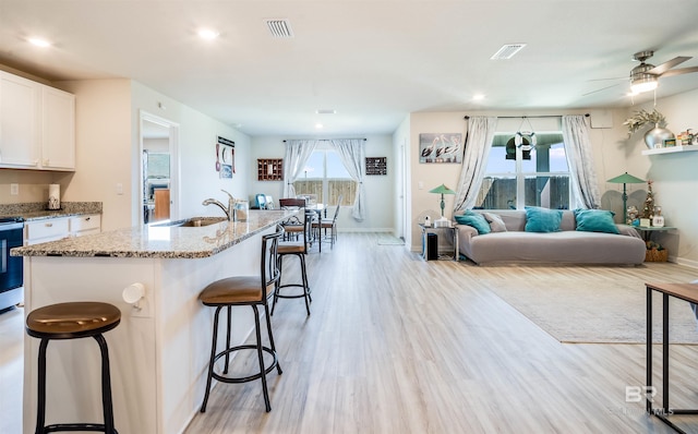 kitchen with a breakfast bar area, a sink, visible vents, and light wood-style floors