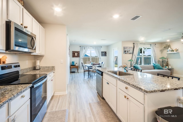 kitchen featuring visible vents, appliances with stainless steel finishes, open floor plan, and a sink