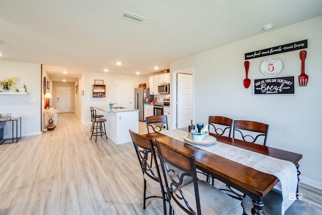 dining space with light wood-style floors, baseboards, visible vents, and recessed lighting