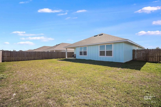 back of property with a fenced backyard and a lawn