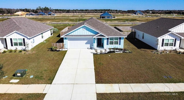 view of front of property with roof with shingles, concrete driveway, an attached garage, a front yard, and fence