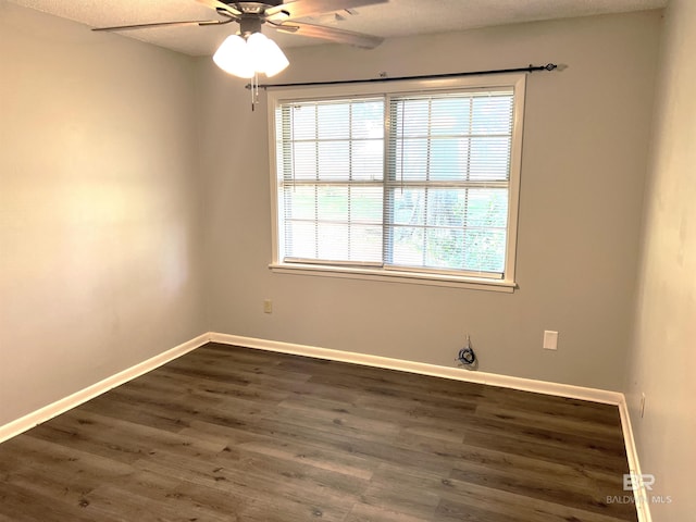 empty room with baseboards, dark wood-type flooring, and ceiling fan