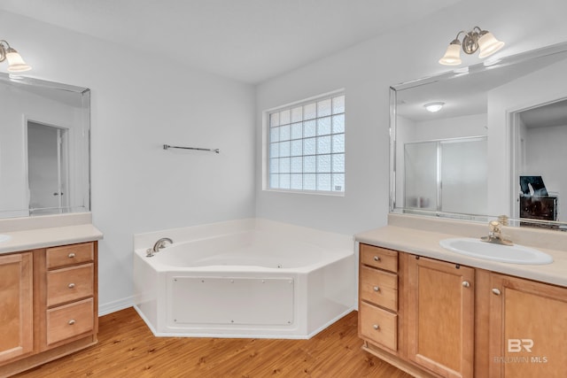 full bathroom with a stall shower, wood finished floors, a bath, and vanity