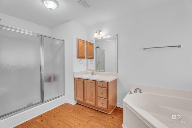 bathroom with visible vents, vanity, a shower stall, wood finished floors, and a bath