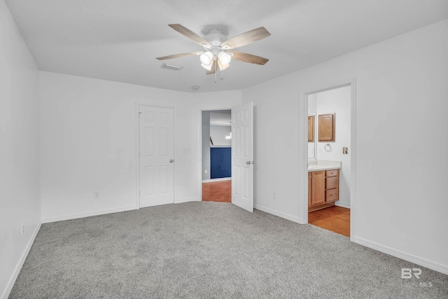 unfurnished bedroom featuring visible vents, ensuite bathroom, light carpet, ceiling fan, and baseboards