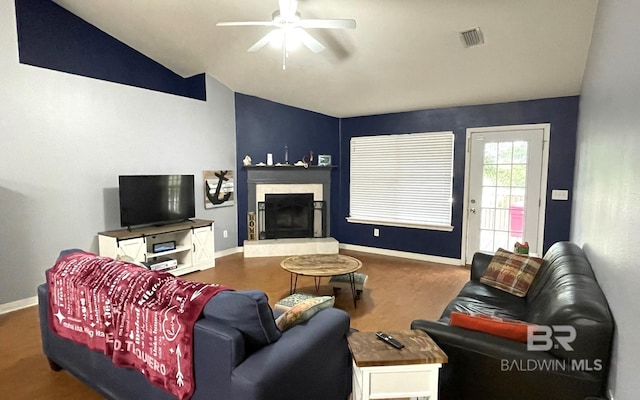 living room with dark hardwood / wood-style floors, a tiled fireplace, ceiling fan, and vaulted ceiling