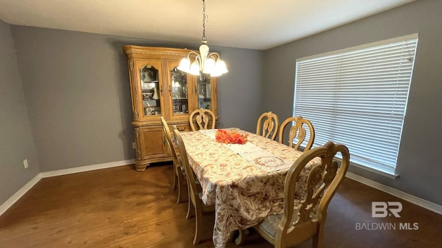 dining space with a chandelier, baseboards, and dark wood-style floors