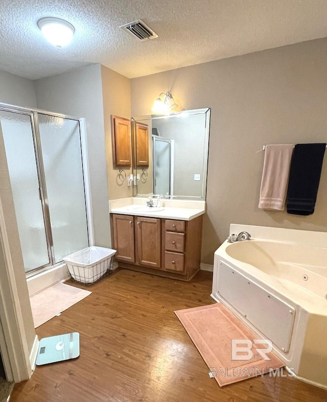 full bath featuring visible vents, wood finished floors, a jetted tub, vanity, and a shower stall