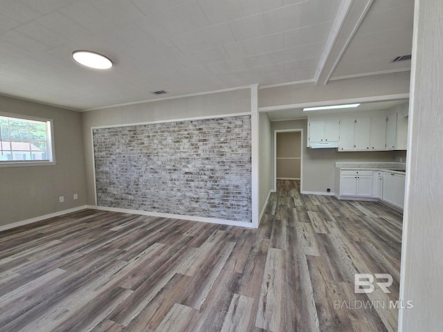 114 Spruce Ave, Brewton, AL 36426 - unfurnished living room with wood finished floors, baseboards, and brick wall