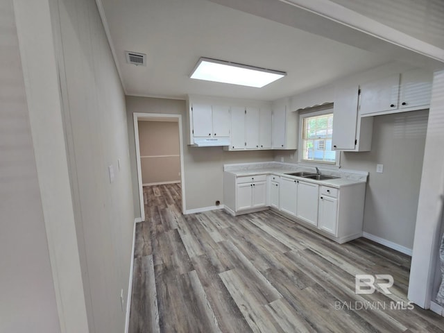 114 Spruce Ave, Brewton, AL 36426 - kitchen with a sink, light wood finished floors, baseboards, and white cabinetry