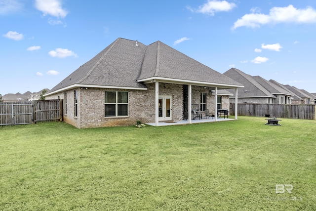 rear view of house with a yard, a patio area, french doors, and an outdoor fire pit