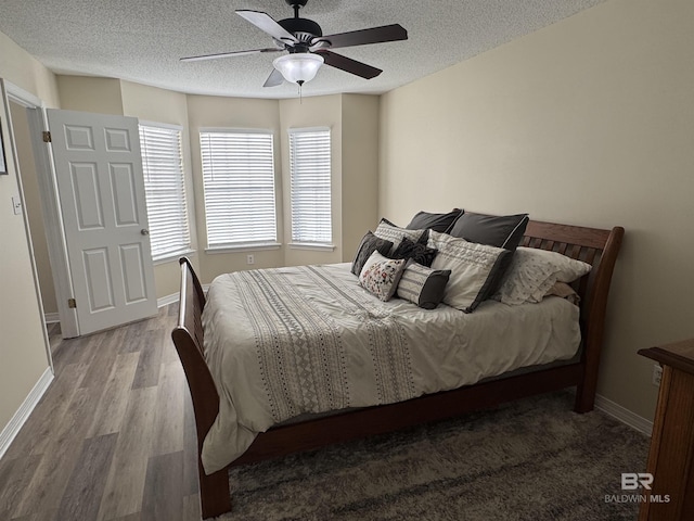 bedroom with baseboards, a ceiling fan, a textured ceiling, and wood finished floors