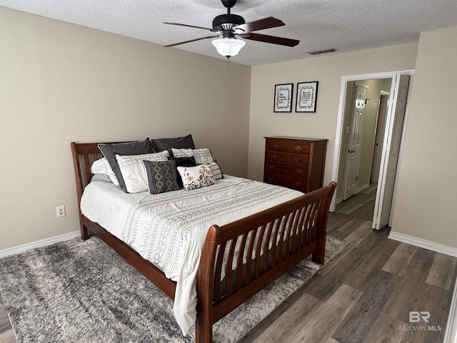 bedroom featuring visible vents, a textured ceiling, baseboards, and wood finished floors
