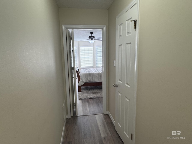 corridor featuring baseboards and dark wood finished floors