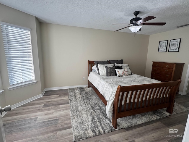 bedroom featuring visible vents, a textured ceiling, ceiling fan, and wood finished floors