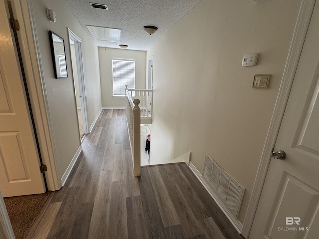hallway with visible vents, an upstairs landing, wood finished floors, and attic access