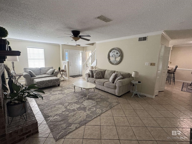 living area with a ceiling fan, tile patterned floors, visible vents, and ornamental molding