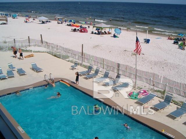 view of swimming pool with a beach view and a water view