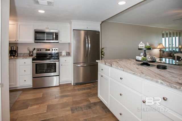 kitchen with light stone countertops, stainless steel appliances, white cabinetry, and dark hardwood / wood-style flooring