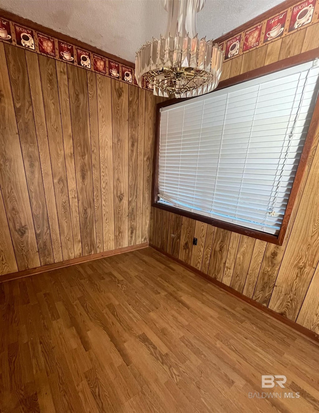 unfurnished dining area with hardwood / wood-style flooring, a textured ceiling, wooden walls, and an inviting chandelier