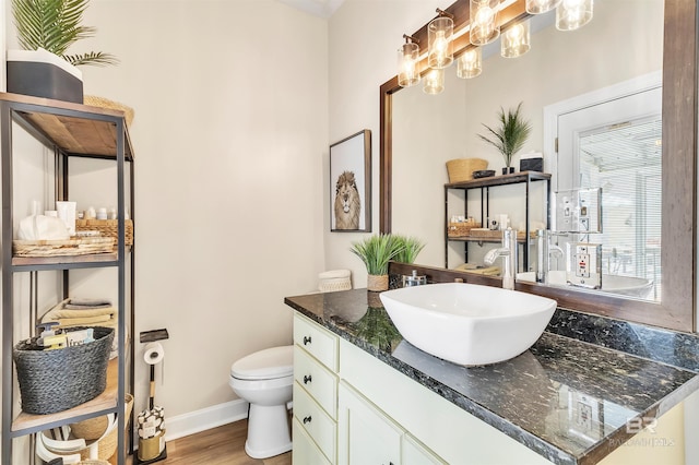 bathroom with vanity, wood finished floors, baseboards, an inviting chandelier, and toilet