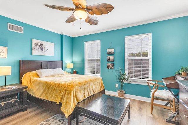 bedroom with visible vents, baseboards, ornamental molding, wood finished floors, and a ceiling fan