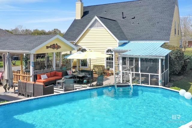 pool with an outdoor living space, a patio area, and a sunroom