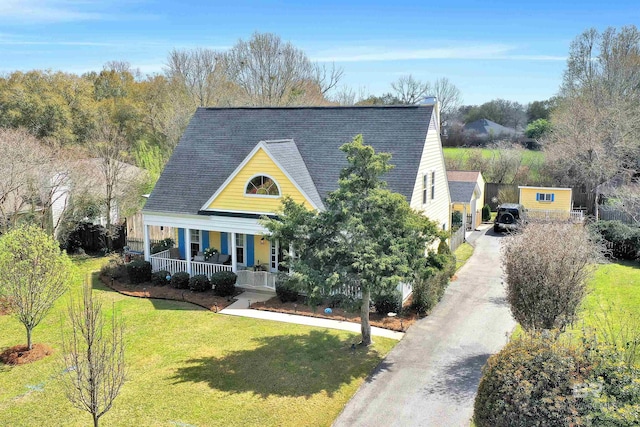 view of front of property with roof with shingles, covered porch, concrete driveway, and a front lawn