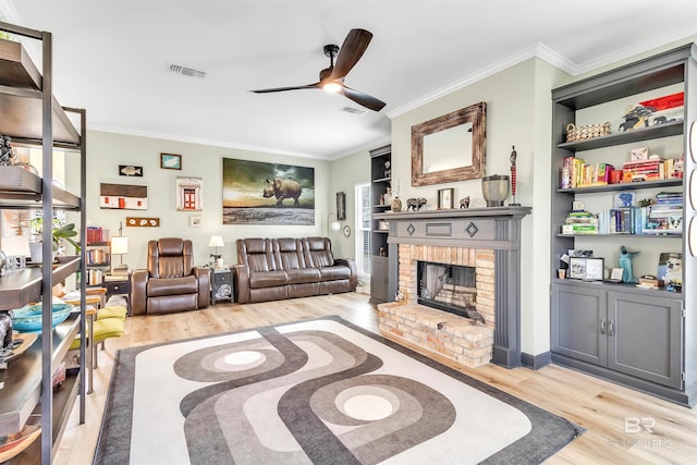 living room featuring visible vents, a brick fireplace, crown molding, light wood-style flooring, and a ceiling fan