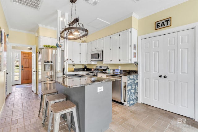 kitchen with visible vents, ornamental molding, appliances with stainless steel finishes, brick floor, and a sink