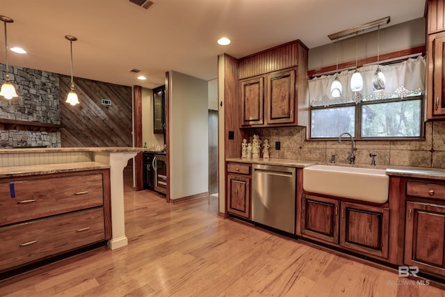 kitchen featuring sink, stainless steel dishwasher, decorative light fixtures, and light hardwood / wood-style floors